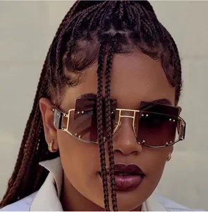 Detail of oversized gold metal sunglasses with brown gradient lenses and silver rivets