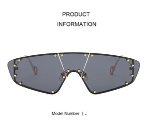 Front view of oversized futuristic sunglasses with dark grey lenses and gold metal studs