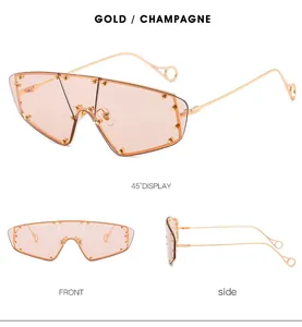 Detail view of champagne shield sunglasses with gold metal frame and stud accents