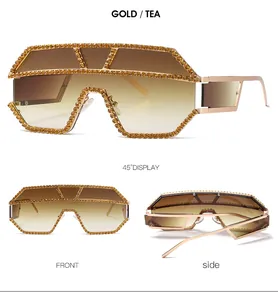 Dettaglio di occhiali da sole oversize dorati con strass e lenti color tè sfumate