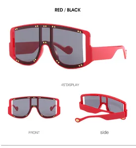Detail view of red oversized shield sunglasses with gold stud accents and dark gray lenses