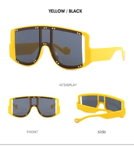 Detail view of yellow oversized sunglasses with decorative gold metal rivets and dark lenses