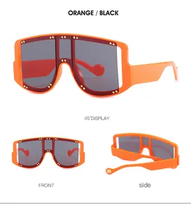 Detail of orange oversized sunglasses with gold stud accents and dark grey lenses