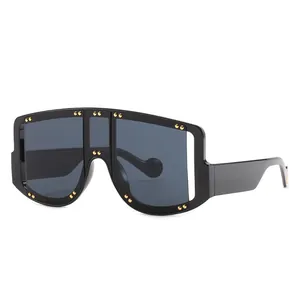 Oversized one-piece shield sunglasses with black frames and golden rivet accents