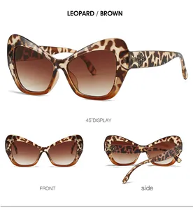 Detalle de gafas de sol cat-eye de leopardo con logo de flor de metal y lentes degradadas