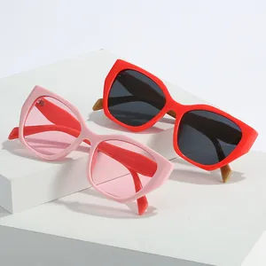 Lunettes de soleil œil de chat polygone irrégulier en rose et rouge sur socles blancs