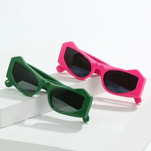 Neon green and pink cat-eye sunglasses with thick geometric frames on a white platform