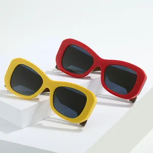 Schicke Oversized-Sonnenbrille in Rot und Gelb mit quadratischem Rahmen auf weißem Podest
