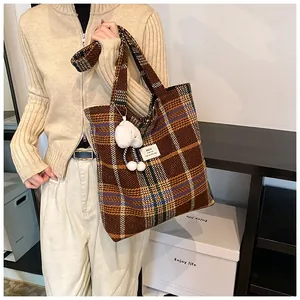 Dettaglio laterale di borsa tote a quadri marroni con ciondolo a forma di nuvola bianca