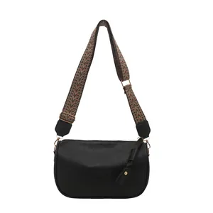 Minimalist black PU leather pillow bag with a colorful ethnic woven shoulder strap