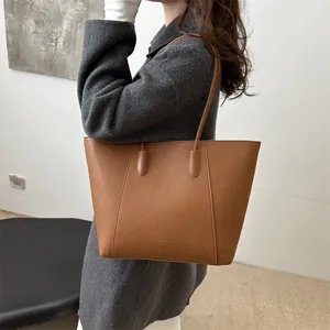 Brown lychee leather tote bag with large capacity for women shown on shoulder of a model