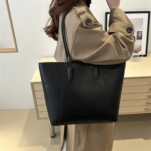 Minimalist black lychee leather tote bag with long straps shown on a model for daily use
