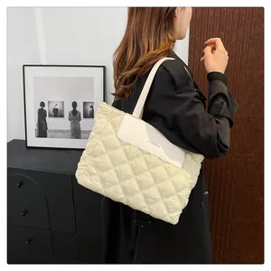 Detail of cream quilted tote bag featuring a leather flap with FASHION embossed lettering