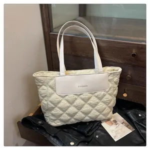 Close-up of quilted cream tote bag with rhombic pattern and fashion leather patch detail