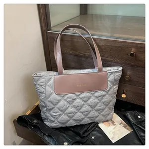 Close-up of quilted grey tote bag with pink leather fashion label and contrast handles