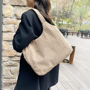 Bolso tote grande de pana beige usado al hombro por una modelo con un diseño elegante