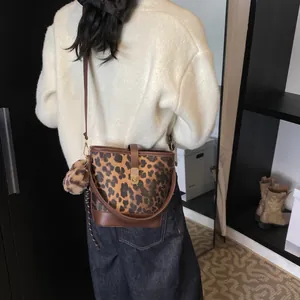 Leopard-Beuteltasche mit braunem Lederbesatz und Bommel-Anhänger am Model gezeigt