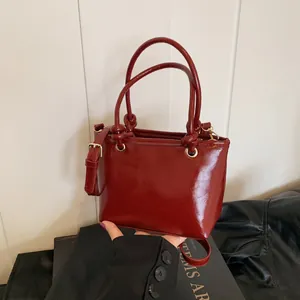 Deep red oily leather handbag for women featuring a minimalist bucket design and crossbody strap