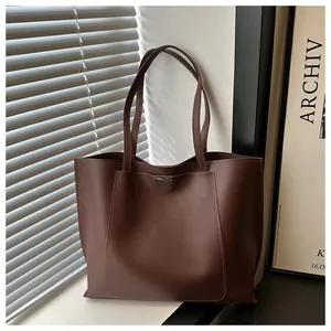 Gros plan d'un sac cabas en cuir PU marron foncé avec détails métalliques élégants