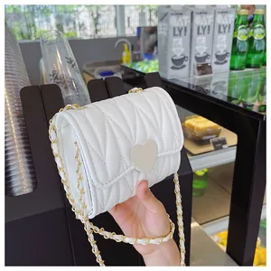 Dettaglio mini borsa trapuntata bianca con fibbia a cuore e catena dorata