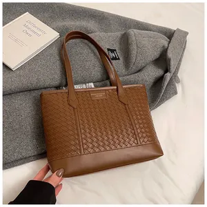 Détail du sac cabas en similicuir tressé marron avec texture classique et étiquette mode
