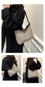 Detail view of monogrammed canvas hobo bag with brown leather trim and shoulder strap