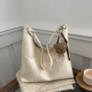 Bolso tote de cuero suave beige con correa anudada y colgante de oso de peluche