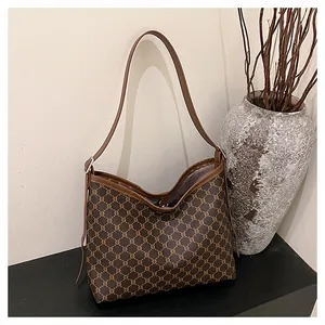 Detailed view of brown monogram tote bag with leather trim on a minimalist display
