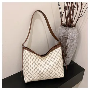 Detail of vintage monogram tote bag featuring ivory canvas with brown leather strap