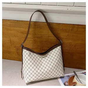 Detailed view of the vintage monogram pattern and brown leather trim on a retro tote bag