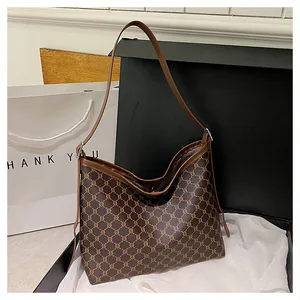 Detailed close-up of brown monogram tote bag with leather strap in elegant gift packaging