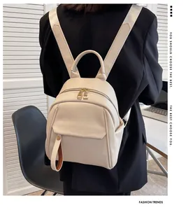 Modern cream faux leather backpack with pebble grain texture shown on model in studio