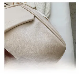 Macro shot of high-quality lychee grain leather and neat stitching on beige backpack