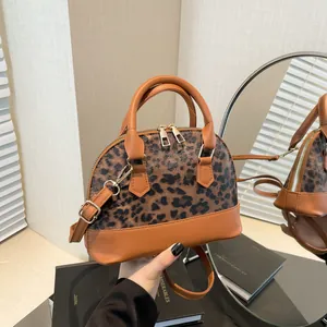 Elegant leopard print shell bag in brown leather with top handles and golden zipper detail