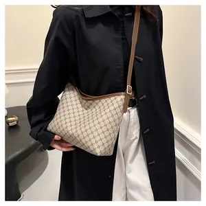 Detail of vintage retro hobo bag worn by model over a black coat with leather shoulder strap