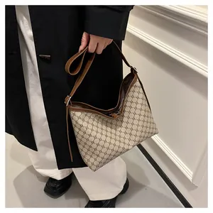 Classic khaki and brown monogram hobo bag worn with a chic black coat and white trousers