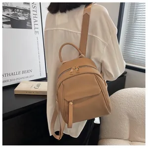 Lifestyle shot of a woman wearing a khaki lychee pattern leather mini backpack
