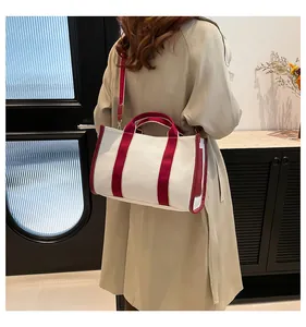 Detail of canvas tote bag with burgundy straps styled on a woman wearing a trench coat