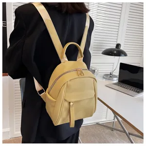 Detail shot of a small mustard yellow backpack on a model with premium lychee grain texture