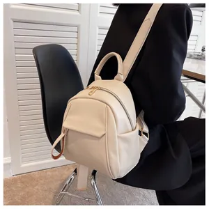 Side view of cream leather mini backpack with gold zippers shown on a female model