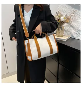 Lifestyle shot of a canvas handbag with brown leather trim and wide adjustable shoulder strap