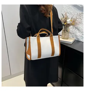 Detail of striped canvas tote bag showing brown straps and adjustable shoulder strap style