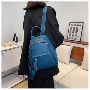 Blue lychee-textured leather backpack with gold zippers and wide shoulder straps on a model