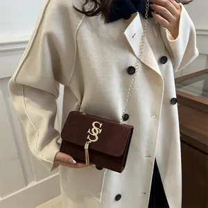 Dark brown suede mini crossbody bag with gold logo, tassels, and chain strap for women