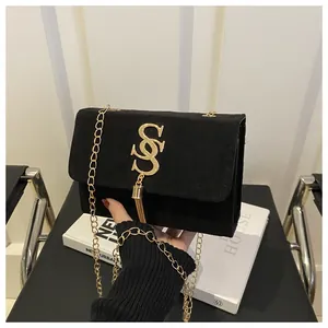 Black suede-textured crossbody bag with gold logo hardware and fringe detail