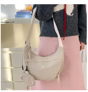 Detail view of beige nylon crescent bag featuring multiple zippers and a round coin purse
