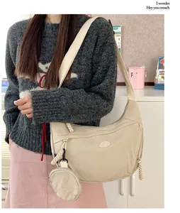 Detail view of beige nylon crescent crossbody bag with small round coin purse attachment