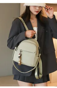 Dettaglio dello zaino in pelle verde chiaro con ciondolo a cartone su modella