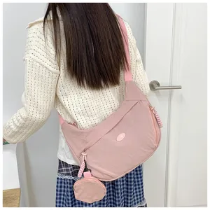 Pink crescent nylon crossbody bag with matching round pouch shown on female model back