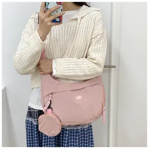 Detail of pink canvas crossbody bag featuring a round coin purse and wide shoulder strap